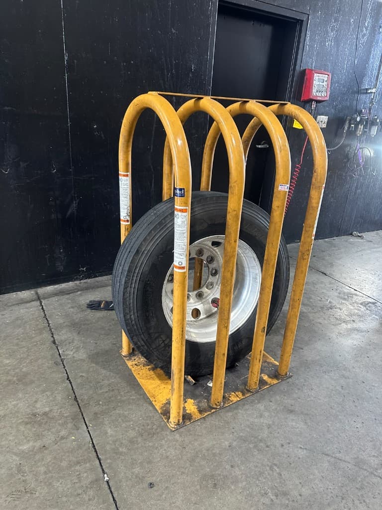 Commercial truck tire secured in a yellow safety inflation cage